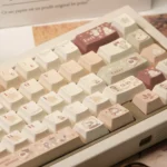 Luxurious Caramel PBT Keycaps set, shown from various angles, highlights the cozy winter haven aesthetic in comforting cream and brown.