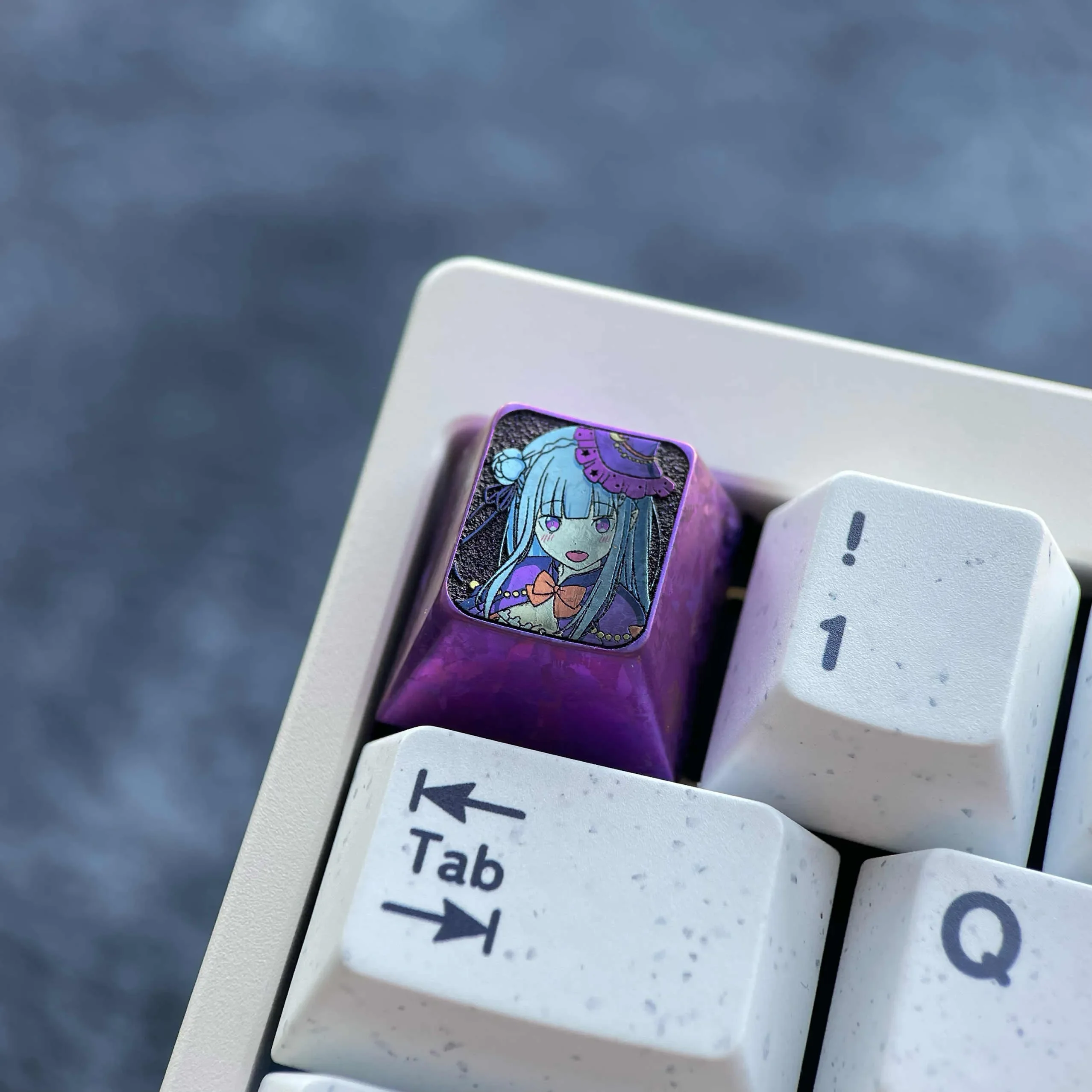 Emilia Titanium Keycap: Premium artisan metal keycap in anodized purple, showcasing its mystical Halloween character design from various angles.