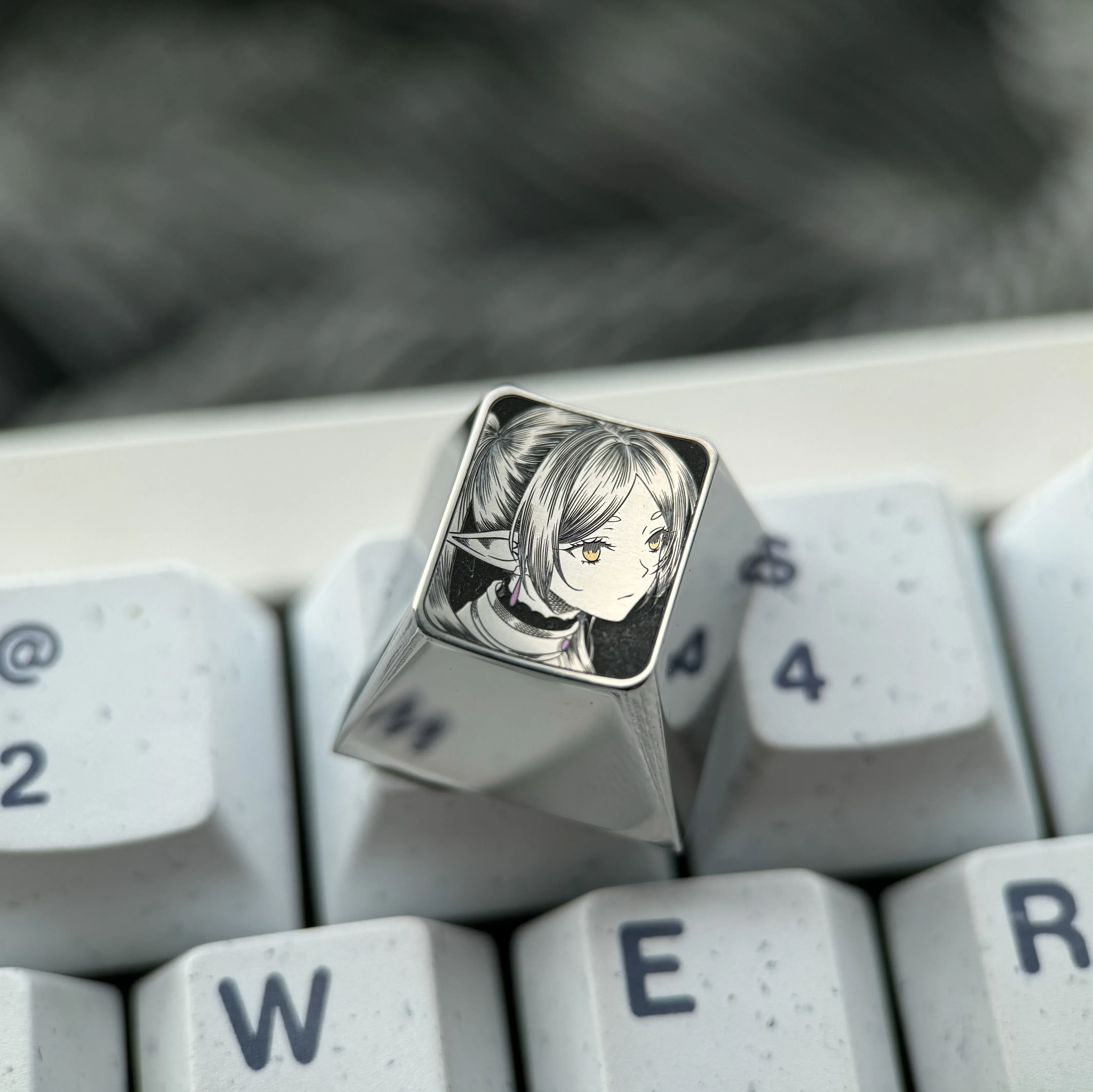 Hand-sculpted Frieren keycap in mirror-finish titanium, showcasing a precision-carved Frieren portrait with intricate stippling.