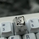 Gallery of the hand-sculpted titanium Frieren keycap, showcasing the precision-carved anime portrait and intricate stippling from various angles.