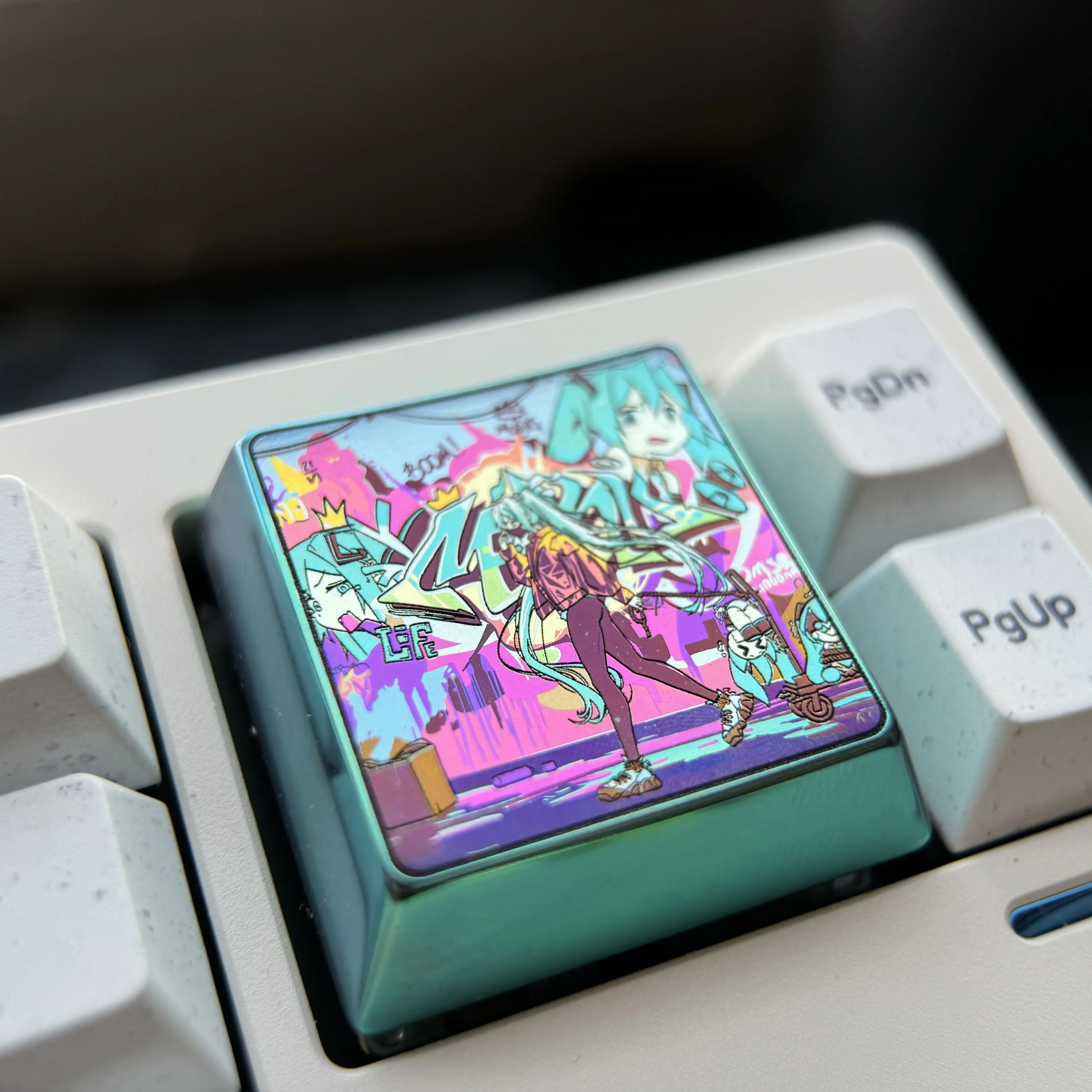 Experience the iconic Hatsune Miku premium titanium alloy keycap from multiple angles, revealing its vibrant anime art and iridescent futuristic design.