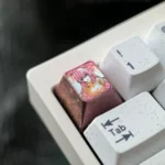 Multiple angles of the exclusive Ichinose Honami titanium keycap reveal vibrant anime art on its lustrous metallic surface, highlighting premium deisgn.