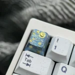 Hand-carved titanium Van Gogh Starry Night keycap from multiple angles, revealing its intricate celestial landscape relief and captivating metallic design.