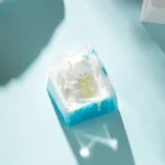 Artistic handcrafted resin Ice World keycap, showcasing its whimsical miniature ice world diorama and adorable cartoon penguin from multiple angles.