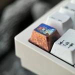 Multiple angles showcasing the Wuthering Waves: Changli Titanium Keycap, highlighting its intricate design and polished metal finish.