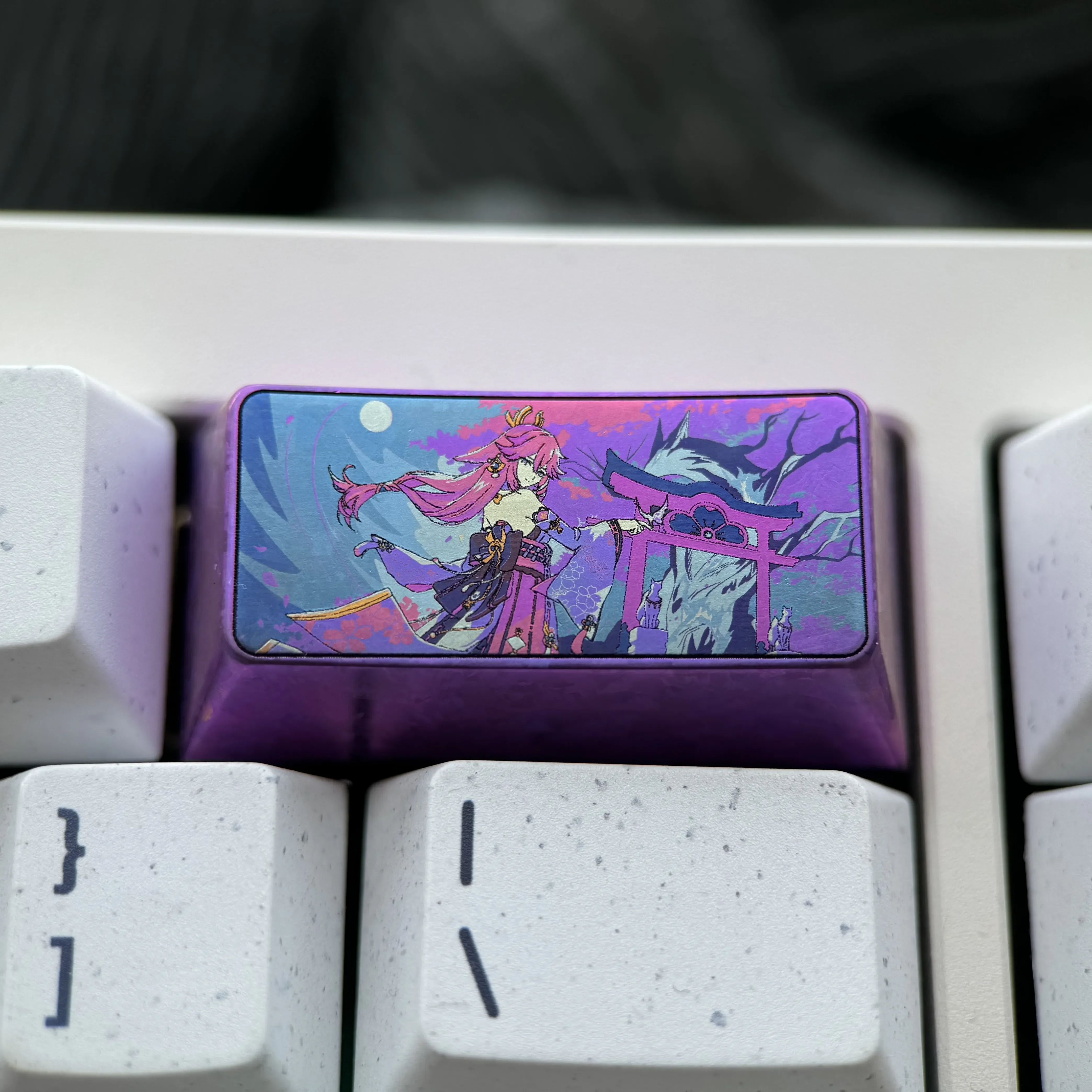 Close-up of a premium titanium Yae Miko 2U backspace keycap, featuring vibrant anime art and a luxurious polished finish. The ultimate Yae Miko design.