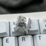 Product gallery of the artisan 2B Titanium Keycap, revealing its iconic Nier Automata 2B precision engraving and metallic finish from various angles.