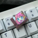 Showcasing the iconic Anya Forger titanium alloy keycap from various angles, emphasizing its vibrant anime art and premium, durable finish.