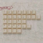 Exquisite Art Nouveau keycaps from the pbt set, showcasing intricate floral motifs and organic flowing lines in soft, muted palette.