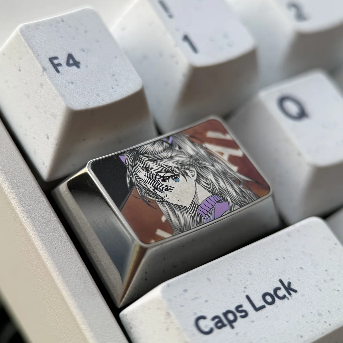 Close-up views of the Iconic Asuka Keycap from various angles, highlighting its bold anime art, metallic luster, and precision engraved details.