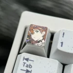 Close-up of the precision-carved Asuka keycap, revealing its intricate anime character design and polished metallic finish.