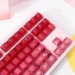 A playful gallery view of luminous, transparent cinnabar pink keycaps set, showcasing their delicate gradient glow and charm from multiple angles.