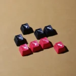 A playful set of iconic translucent CSGO weapon keycaps, illuminated from various angles, showcasing vibrant red and black designs.