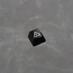 Close-up of a black Electric Hazard danger keycap, featuring a striking backlit red and yellow industrial warning symbol. Edgy, high-contrast design.