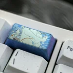 Multiple views of the Frieren Keycap, showcasing the handcrafted colorful titanium, intricate Elven Mage details, and vibrant finish for a 2U keycaps.