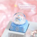 Artistic gallery showcasing the Interactive Snowman Keycap. Reveals its miniature crystal ball winter scene with a blue snowman, falling snowflakes.
