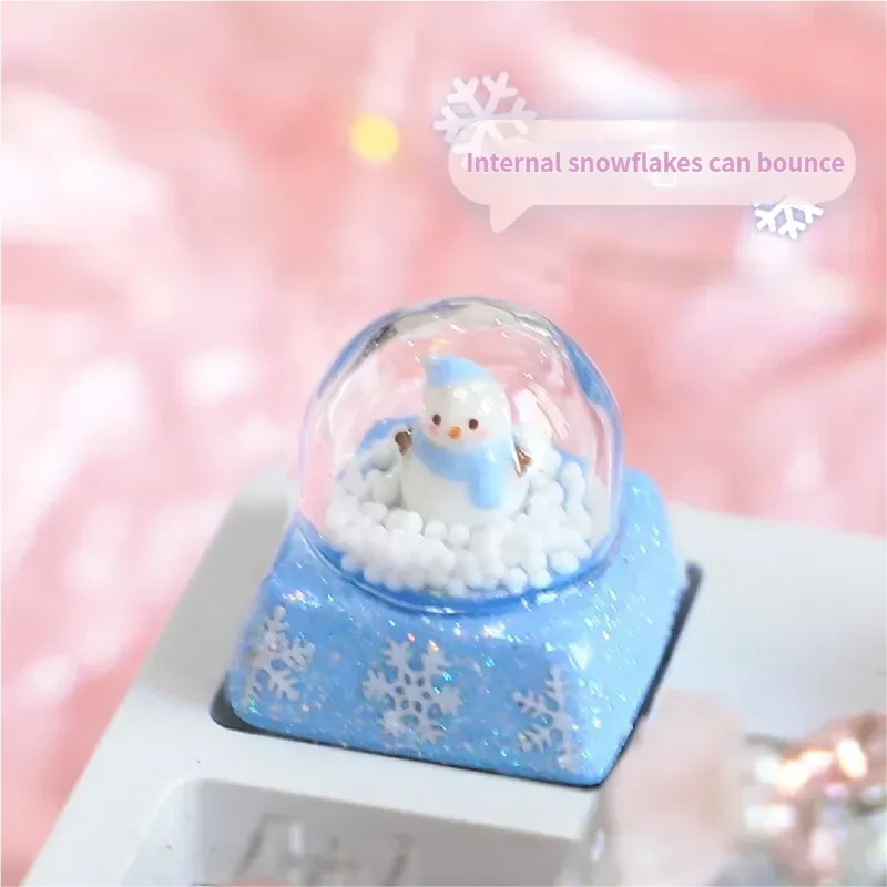 Artistic gallery showcasing the Interactive Snowman Keycap. Reveals its miniature crystal ball winter scene with a blue snowman, falling snowflakes.