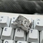 Gallery of the artisan Premium Titanium Ishtar & Ereshkigal Tab Key Keycap, revealing its precision-engraved Fate anime motifs and gleaming metallic surface from various angles.