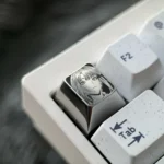 Detailed gallery of the precision-engraved Makima Titanium Keycap, highlighting intricate pointillism art and sleek silver finish from various angles.