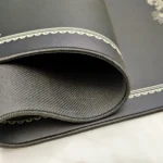 Gallery of the MEGALOBOX Nomad desk mat, displaying its iconic gritty anime art, waterproof top, and anti-slip base from various angles.