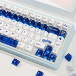 A collection of luminous ceramic-like PC keycaps se in sapphire blue and pure white, showcasing their clean, premium design from multiple angles.