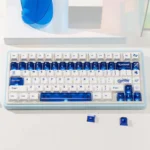 Luminous ceramic PC keycaps set in sapphire blue and pure white, shown from multiple angles, highlighting their clean, premium finish and radiant glow.