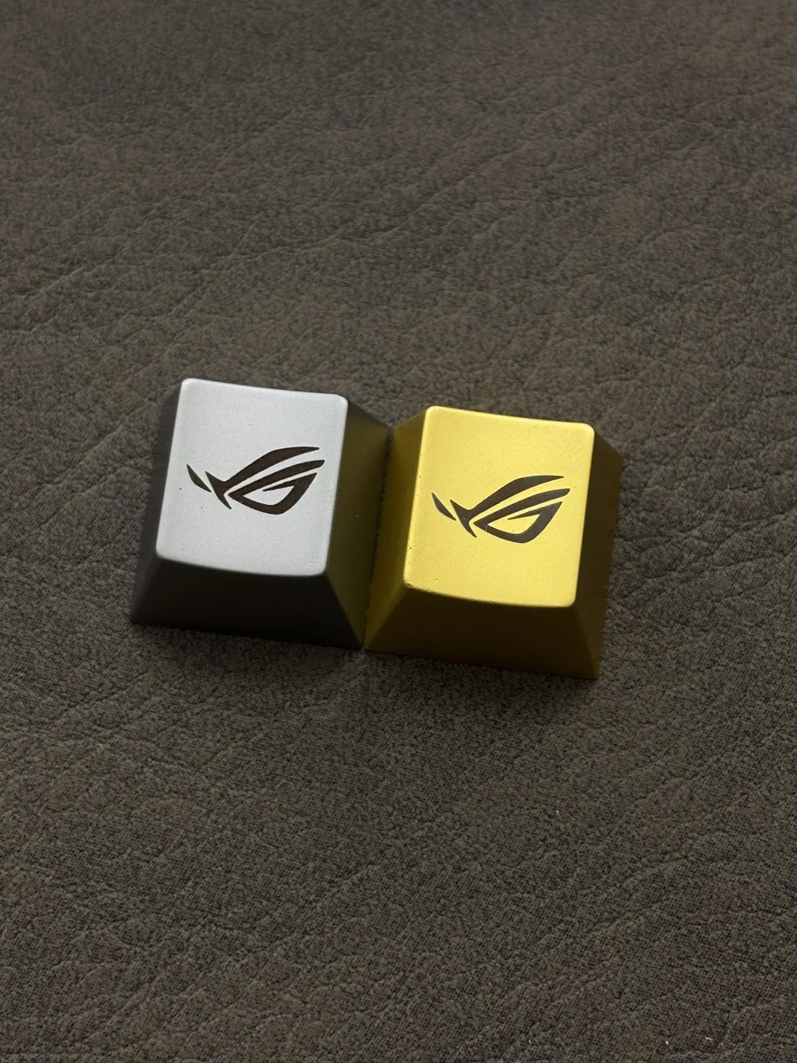 Close-up of the iconic Republic of Gamers: ROG Logo Alloy Keycaps, featuring its aggressive angular design and a premium metallic finish. Elevate your gaming keyboard.