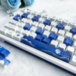 Starry PBT keycap set for mechanical keyboards. Various angles show deep blue cosmic design, twinkling stars, and celestial map.