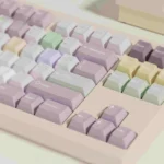 A whimsical gallery of Taro Pistachio Keycaps Set showcasing their sweet pastel purple, green, and cream dessert-inspired aesthetic from various angles.