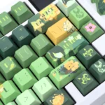 Exclusive Tighnari Genshin Impact PBT keycaps set shown from multiple artistic angles, highlighting vibrant forest green designs and detailed characters.