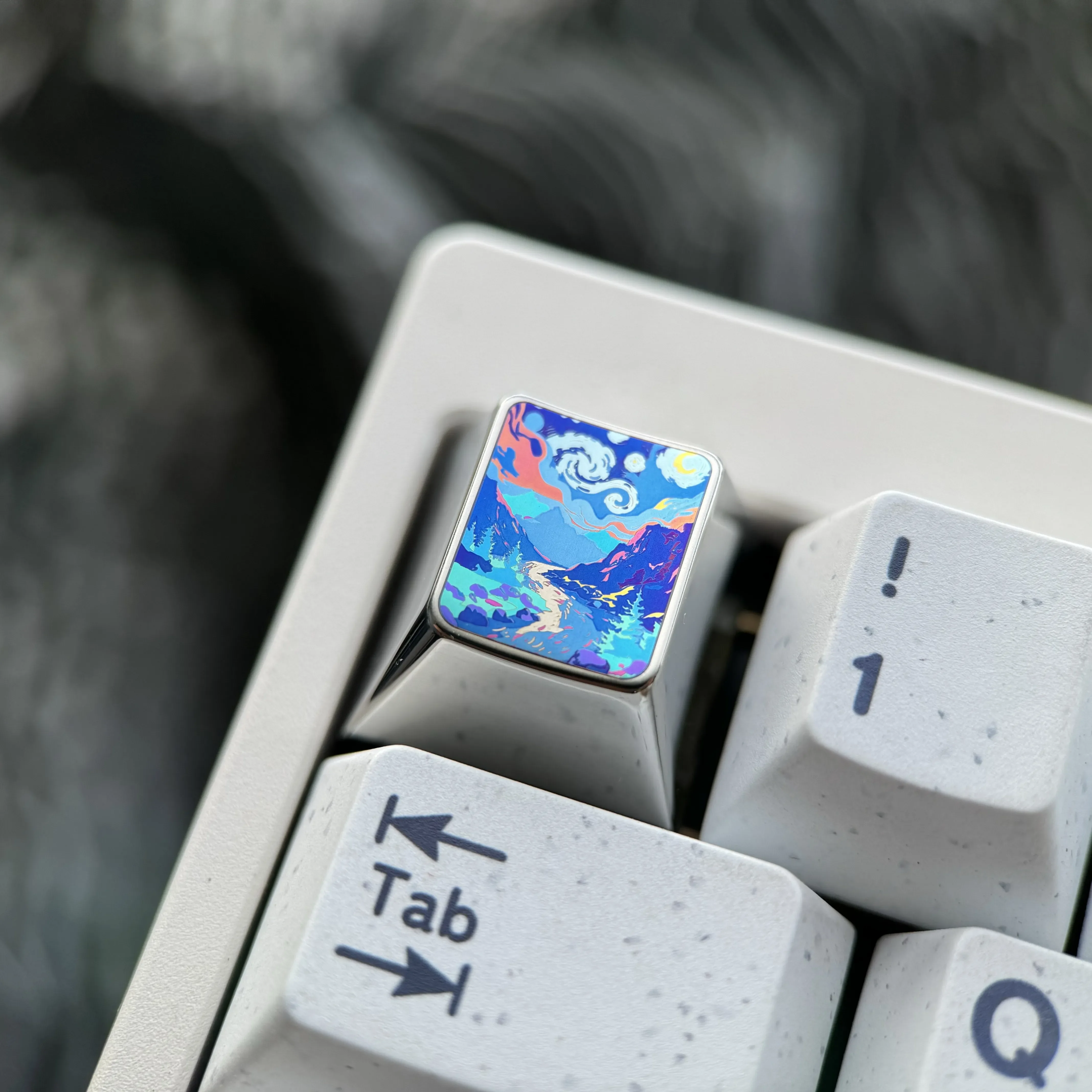 Detailed shot of the handcrafted titanium artisan keycap, showing its unique sculpted mountain valley design and vibrant fade-resistant metallic finish.