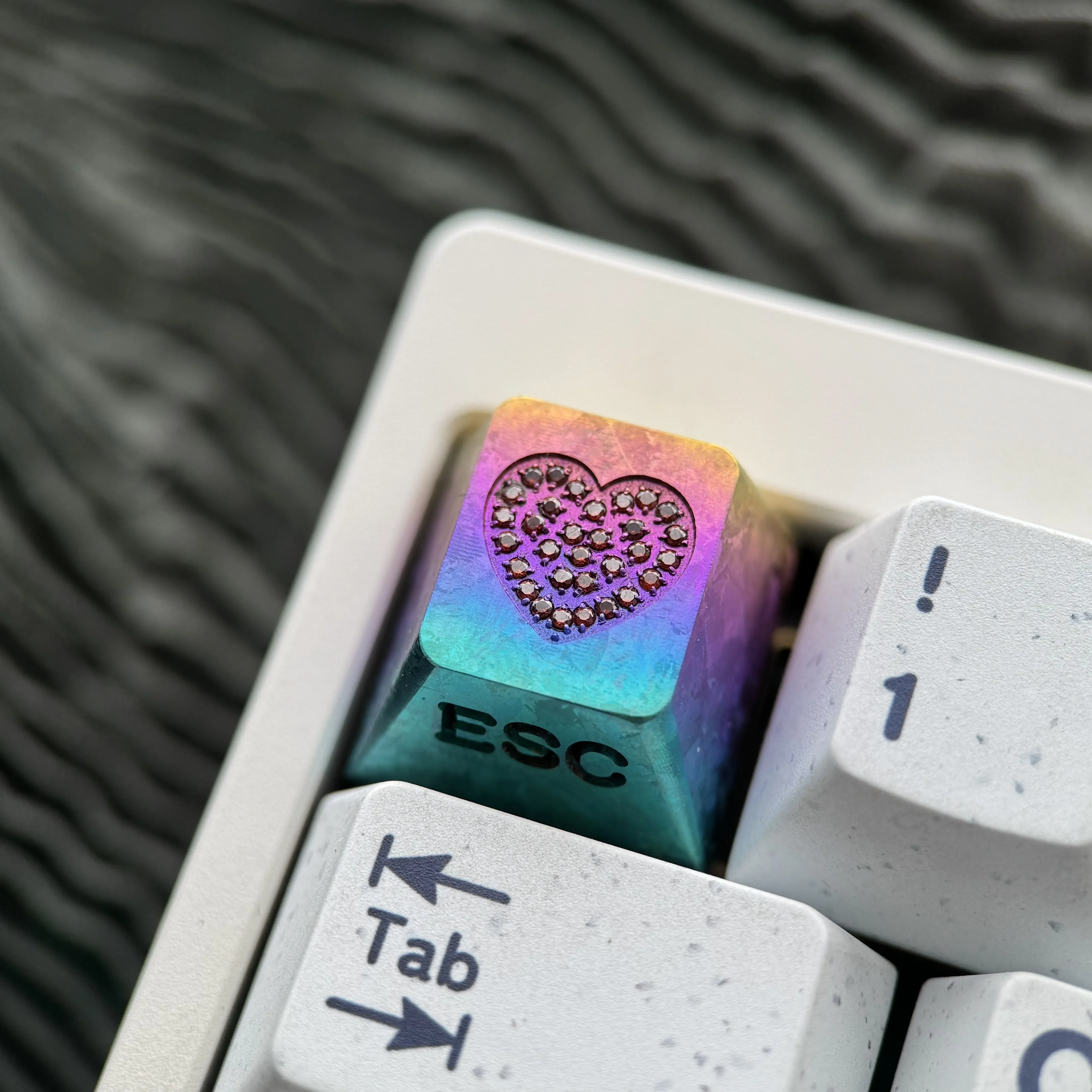 Gallery views of the handcrafted RGB titanium keycap, highlighting the sparkling gemstone heart inlay and intricate custom engravings with radiant design.