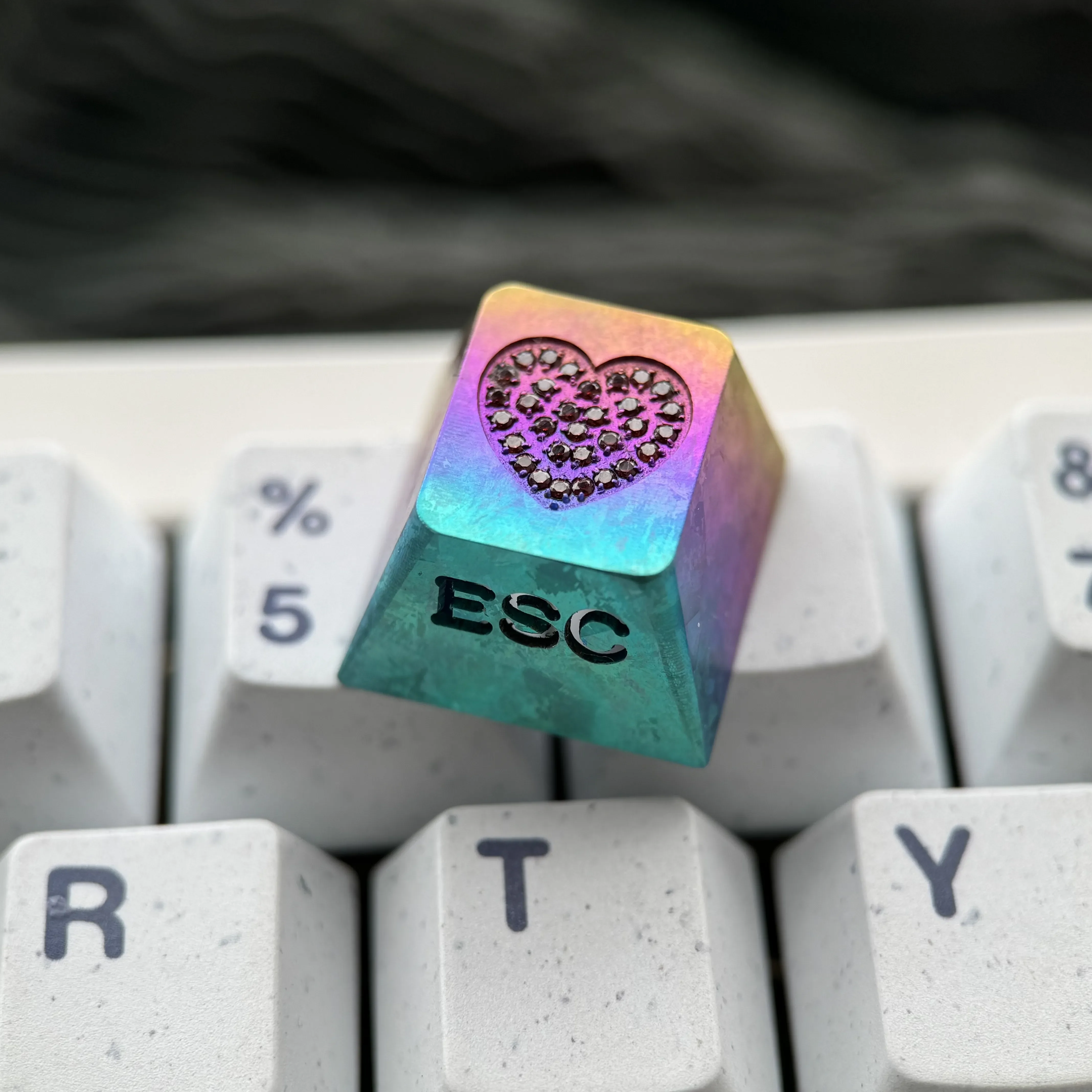 Product gallery of the premium handcrafted titanium keycap, showcasing its sparkling gemstone heart inlay, intricate side carving, and radiant RGB lightning design.