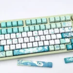 Exclusive Venti-inspired FOA PBT Dye-Sub Keycap Set. Whimsical Venti keycaps in ethereal teal, white, gold, with wind and lyre motifs.