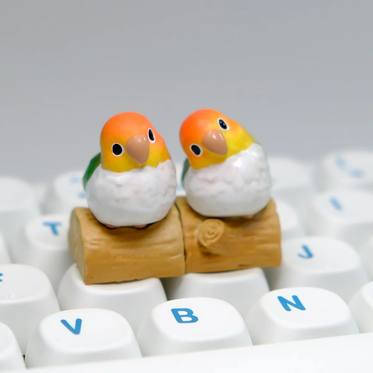 Exquisitely handcrafted vibrant Caique parrot artisan keycap displayed from multiple angles, showcasing its lifelike detail and artistic charm.