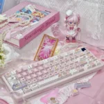 Iconic Cardcaptor Sakura PBT dye-sub keycaps set in playful pastel pink and white, packaged in a box with a keycap puller, capturing magical anime charm.