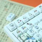Close-up views of adorable Chiikawa Hachiware PBT dye-sub backlit keycaps set, highlighting charming Hachiware art and soft pastel colors from various angles.