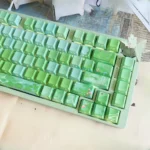 Backlit Chinese art keycaps set gallery, featuring poetic traditional landscapes with green plums and tranquil rain, viewed from various angles.