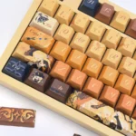 Navia Elegance custom mechanical keycaps set artfully displayed from a distinct angle, revealing intricate amber, gold, and black rose motifs for a premium view.