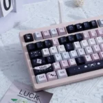 Enigmatic black and vibrant pink artistic PBT keycaps set featuring subtle dye-sub legends, displayed from multiple captivating angles.