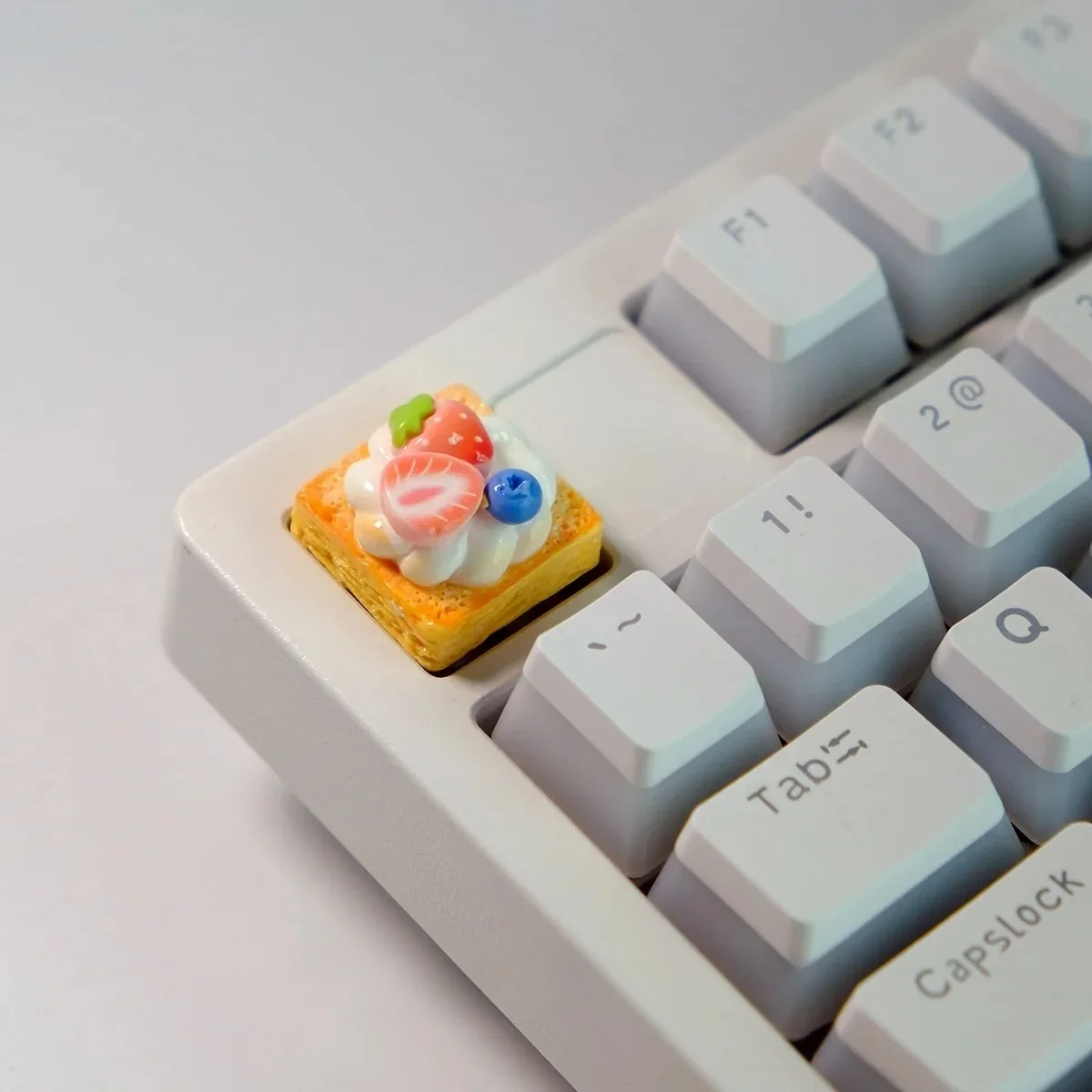 Close-up of a handmade, hyper-realistic Strawberry Mille-Feuille Artisan Keycap from various angles, showcasing its vibrant pink and cream layers.