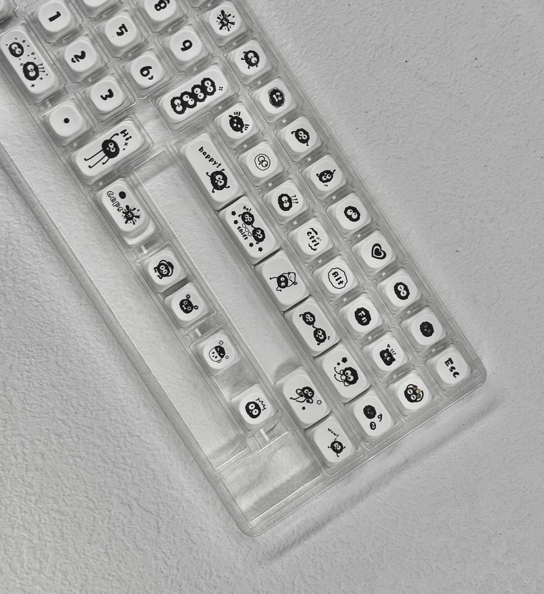 Whimsical Ghibli Susuwatari PBT dye-sub keycaps set, showing various angles. Dark background, playful Soot Sprites for a nostalgic keyboard.