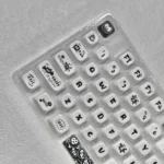 A gallery of whimsical Ghibli Susuwatari PBT Dye-sub keycaps set, showing enchanting characters from multiple angles against a minimalist backdrop.