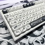 A gallery of whimsical Ghibli Susuwatari PBT Dye-sub keycaps set, showing enchanting characters from multiple angles against a minimalist backdrop.