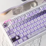 Close-up views of the handcrafted Ethereal Swan Realm Keycap Set, showcasing its translucent amber and deep purple layers from various angles.