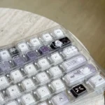 Multiple views of the handcrafted Ethereal Swan Realm Keycap set, showcasing its translucent amber and deep purple double-layer design with an intricate design.