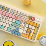 Whimsical claw machine keycap set from a playful side angle, showcasing its intricate miniature arcade design with tiny, colorful prizes.