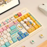 Detailed view of the whimsical claw machine keycap set, highlighting the tiny claw mechanism and the array of playful, miniature prizes from a unique perspective view.