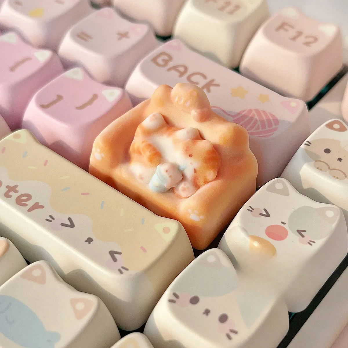 Whimsical hand-sculpted lounging cat keycap in a gallery of views, featuring the charming miniature feline on its cozy, colorful sofa.