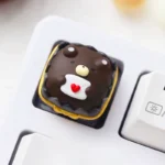 Handcrafted whimsical chocolate animal artisan keycap gallery. Clear resin encases charming, detailed miniature creatures, viewed from multiple artistic view.